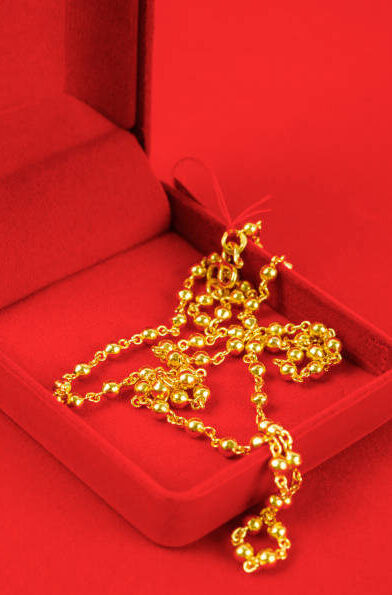 The Gold Necklace in red velvet box container.