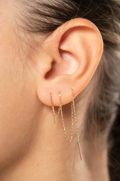 Female ear with three ear chaines. CLose up.
